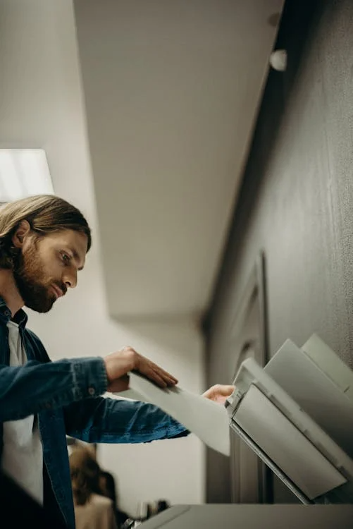 an image of a man putting paper on a printer