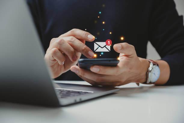 photo of a man's hands scrolling through his phone with an email notification icon